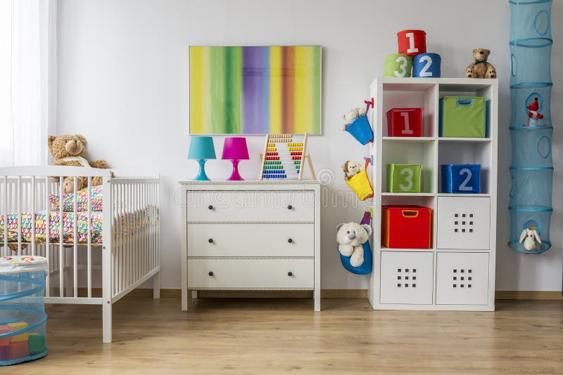 Baby room full of colours. Colorful baby room with a cradle, commode and rack with toys royalty free stock image