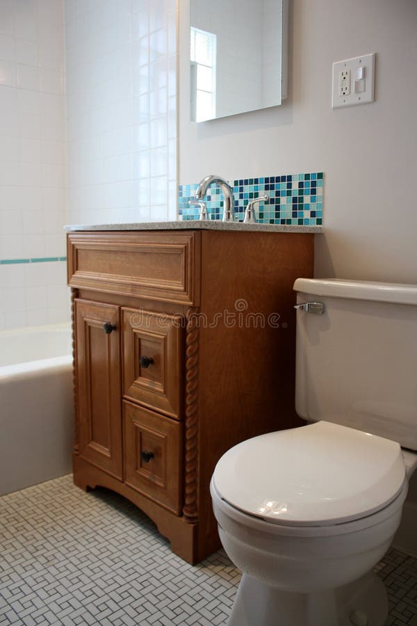 Bathroom with Glass Mosaic Tile. A bathroom with a toilet, vanity, and sink with a mosaic tile backsplash royalty free stock photos