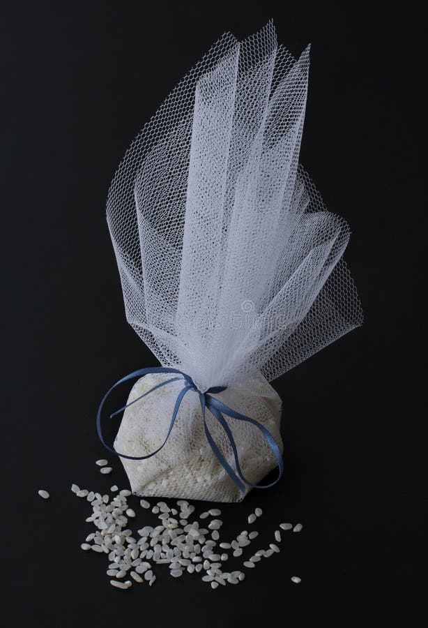 Beautiful white tulle bag of rice shower for wedding ceremony, banquet and wedding ceremony with a little rice lying in front - on stock image