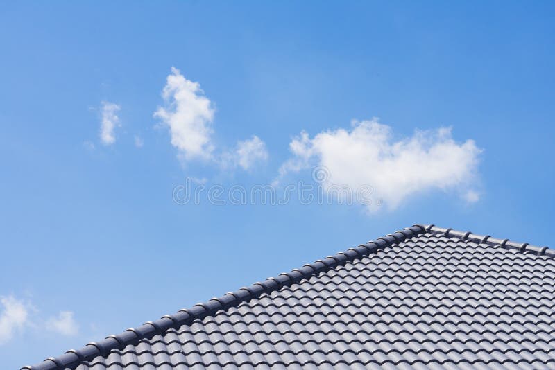 The black tile roof of the new house With a background as bright blue sky and white clouds royalty free stock image