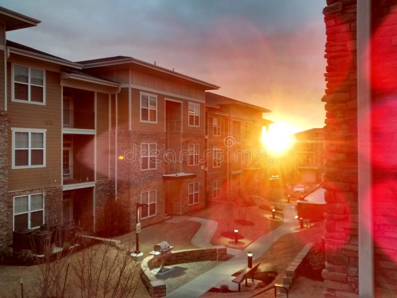 Bright sun beaming through apartment complex. Bright sun beaming through apartment neighborhood with a bbq grill visible by the path royalty free stock photography