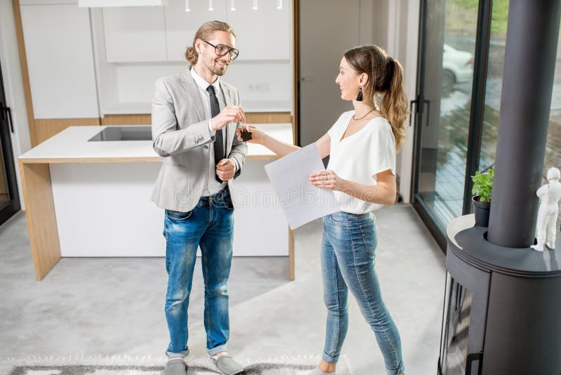 Buying or renting a new apartment. Happy young women buyer standing with realtor receiving keys of a new apartment. New apartment purchase concept stock images