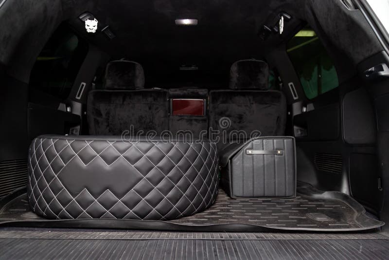 Car spare wheel sheathed in a black leather case and diamond-shaped stitching with white thread in the trunk of an SUV with a tool. Bag on a rubber mat. Auto royalty free stock photos