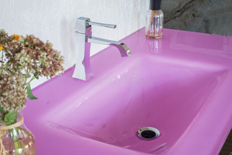 Close-up of a pink stone glossy washbasin, in a fashionable interior, with flowers. View from above stock images