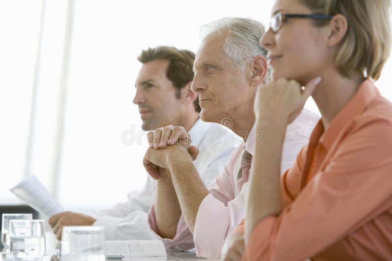 Colleagues Paying Attention In Conference Room. Senior businessman with colleagues paying attention in conference room stock photo