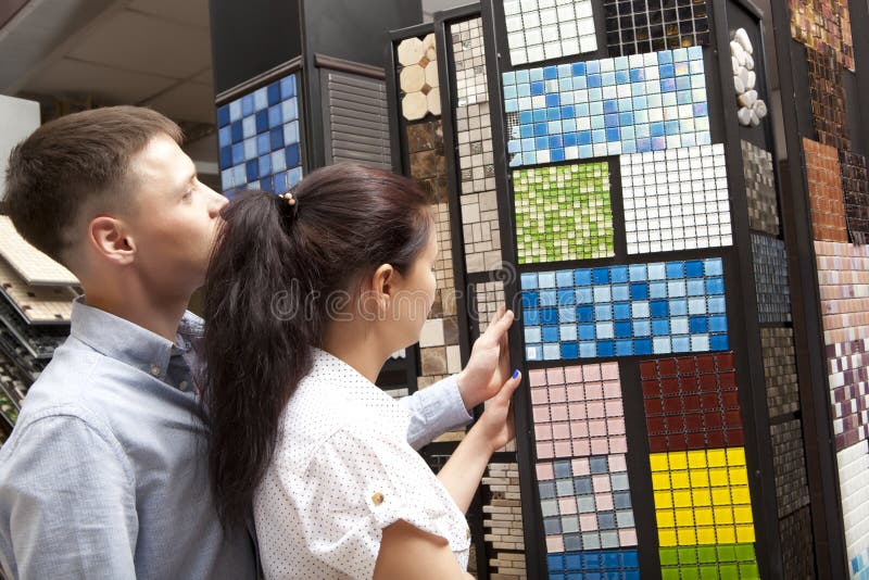 Couple pointing at ceramic mosaic tile for bathroom wall in store. In home improvement warehouse exterior royalty free stock photo