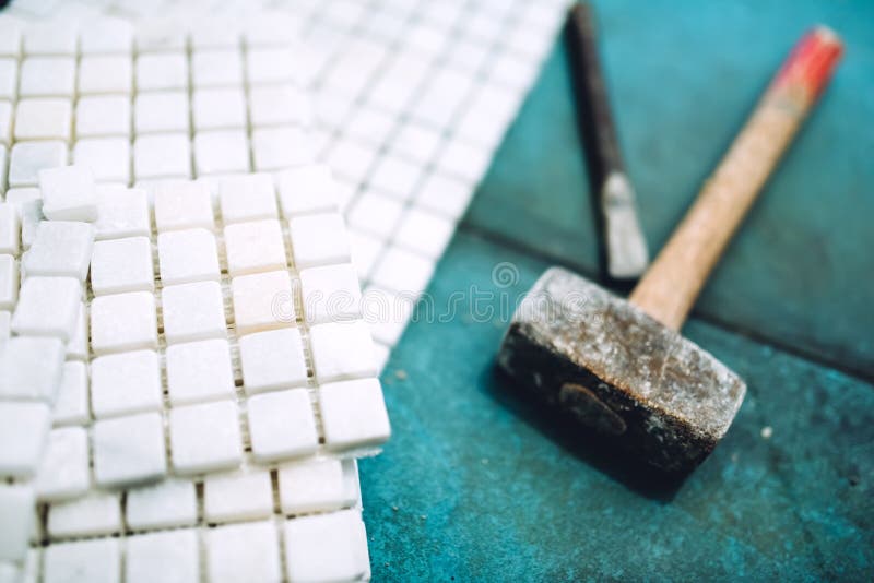 Details of construction tools, bathroom and kitchen renovation - pieces of mosaic ceramic tiles and rubber hammer. Close up details of construction tools royalty free stock photo