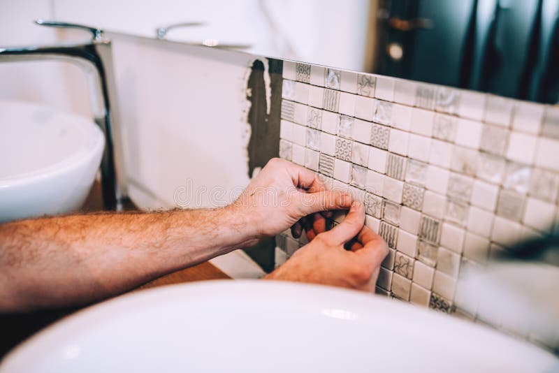 Details of industrial worker applying mosaic ceramic pattern tiles on bathroom shower area. Close up details of industrial worker applying mosaic ceramic pattern royalty free stock photography