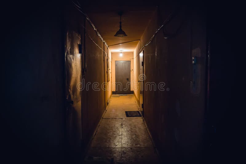Dirty empty dark corridor in apartment building, doors, lighting lamps. Perspective, in yellow-orange tones, copy space stock images