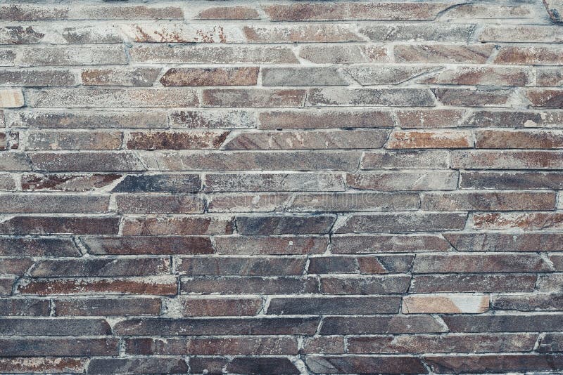 The gray-brown wall is lined with decorative tiles. Light-brown stone wall texture. Rock texture. Brown stone background.  Brick w. The gray-brown wall is lined stock image