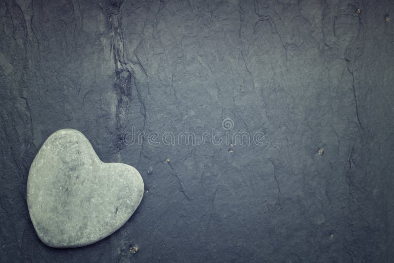 A gray zen heart shaped rock in the corner on a tile background royalty free stock images