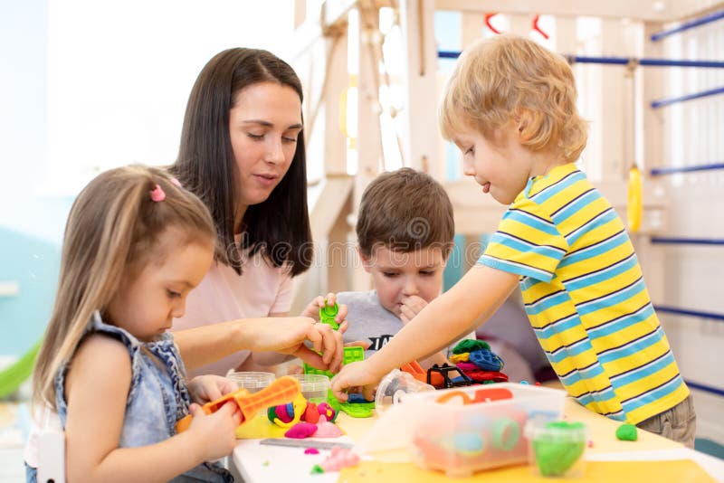 Group of kindergarten children playing with plasticine or dough. Little kids have a fun together with colorful modeling. Group of kindergarten children play with stock photo