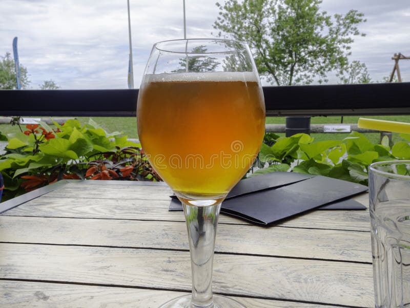 Half glass of beer on a beautiful wooden old table on the veranda of the restaurant. Relax time royalty free stock photography