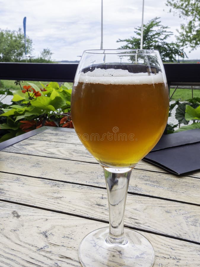 Half glass of beer on a beautiful wooden old table on the veranda of the restaurant. Relax time royalty free stock photography