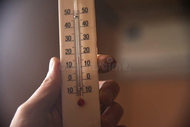 Hand with a white plastic mercury thermometer shows the temperature in the room royalty free stock photography