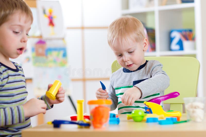 Happy children playing with plasticine at home or day care center. Happy children friends playing with plasticine at home or day care center royalty free stock images