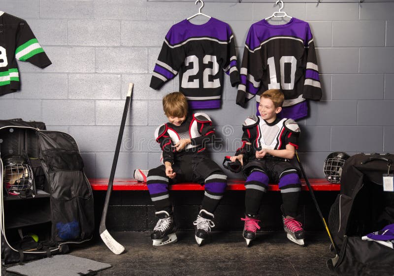 Hockey Arena Boys in Rink Dressing Room. Two Boys Get Dressed in hockey gear in dressing room before game royalty free stock photography