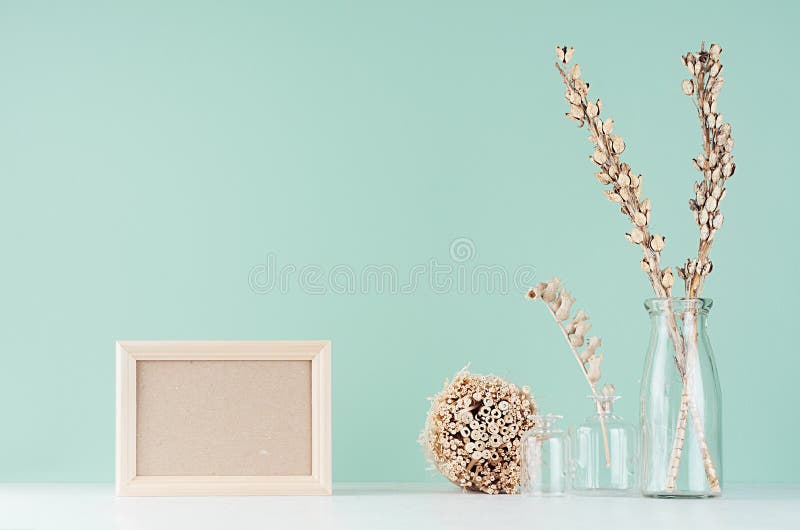 Home decorations in eco style - beige wooden blank frame, dried plant bunch and flowers in glass vase in green mint menthe. Home decorations in eco style stock images