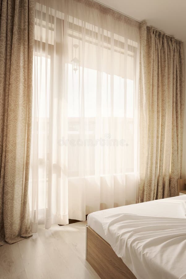 Hotel interior. Long beige curtains and tulle curtains, sheers on a window in the bedroom. Interior design concept.  royalty free stock photography