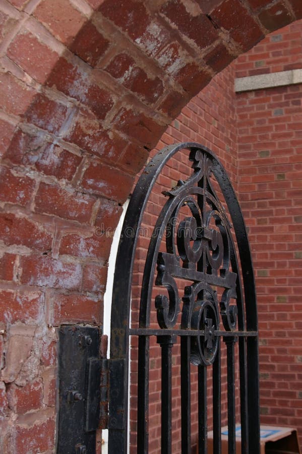 A Metal Gate Guards The Entry to a Brick Courtyard. A swinging metal gate allows entry to a brick courtyard and garden at a country estate royalty free stock photos