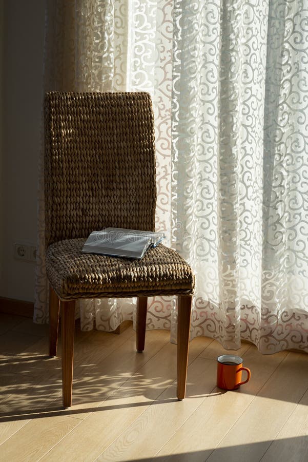 Interior with wicker chair, curtains, book and morning coffe. Design home decor. Sunny morning. Bohemian concept stock images