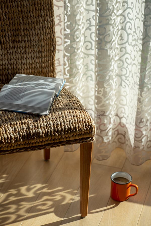 Interior with wicker chair, curtains, book and morning coffe. Design home decor. Sunny morning. Bohemian concept stock image