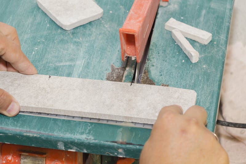 Master cuts the tiles on the saw. repair of apartments and houses. Master cuts the tiles on the saw. repair of apartments and houses royalty free stock photo