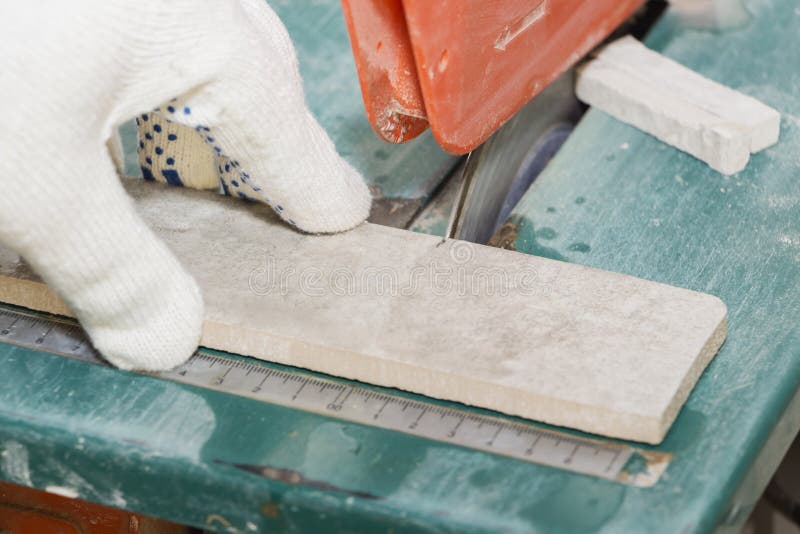 Master cuts the tiles on the saw. repair of apartments and houses. Master cuts the tiles on the saw. repair of apartments and houses royalty free stock images