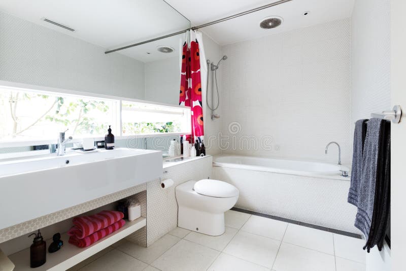 Modern renovated white mosaic tiled family bathroom with red and. Pink accent colors royalty free stock photos