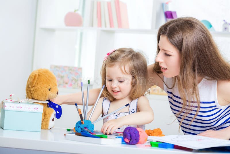 Mom and daughter together. A young mother and her little daughter paint together and made from plasticine and pencils hedgehog. mother and child playing with stock photos