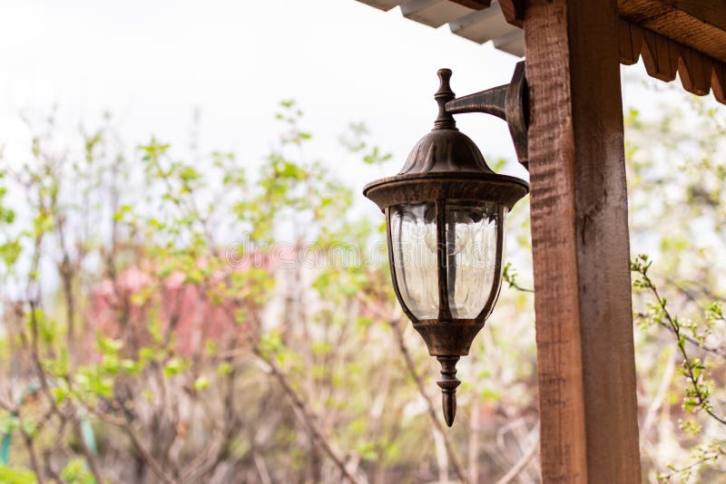 Beautiful old-fashioned lantern hanging on a wooden veranda at the garden house royalty free stock photos