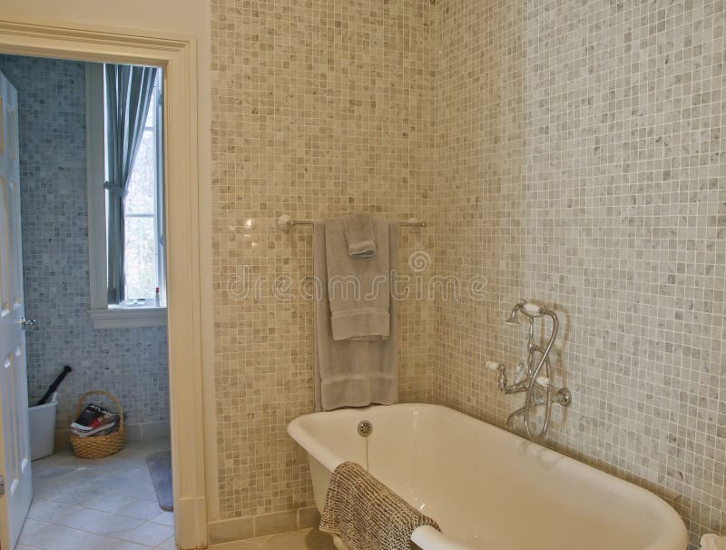 Old Fashioned Tub in Mosaic Tile Bathroom. A mosaic tile bathroom with an old fashioned claw foot bathtub royalty free stock images