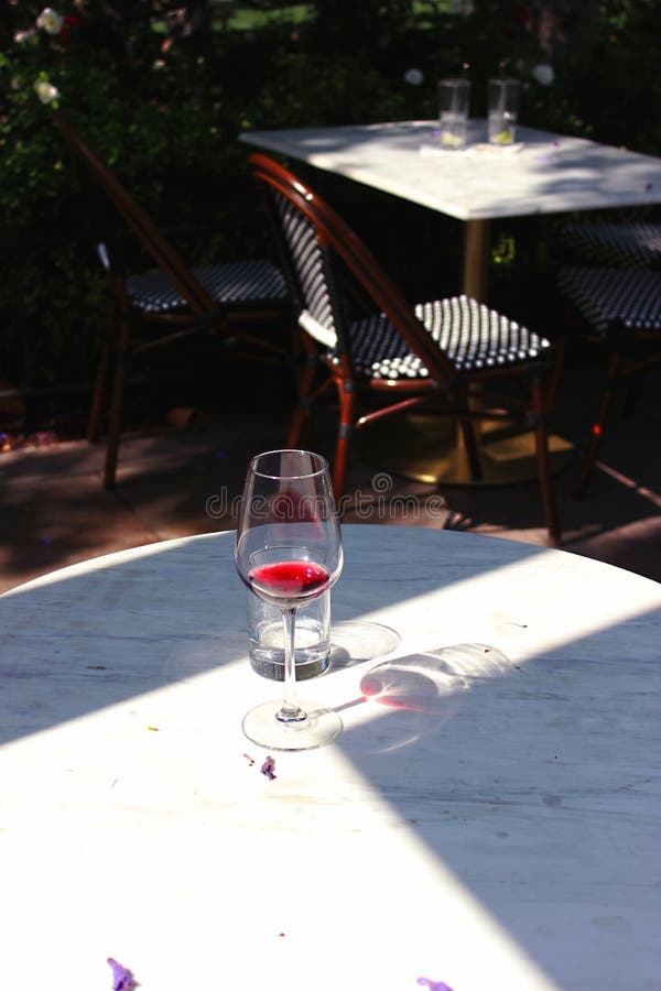 One glass of wine in the cafe on the open veranda. Wine at the bottom of the glass stock image
