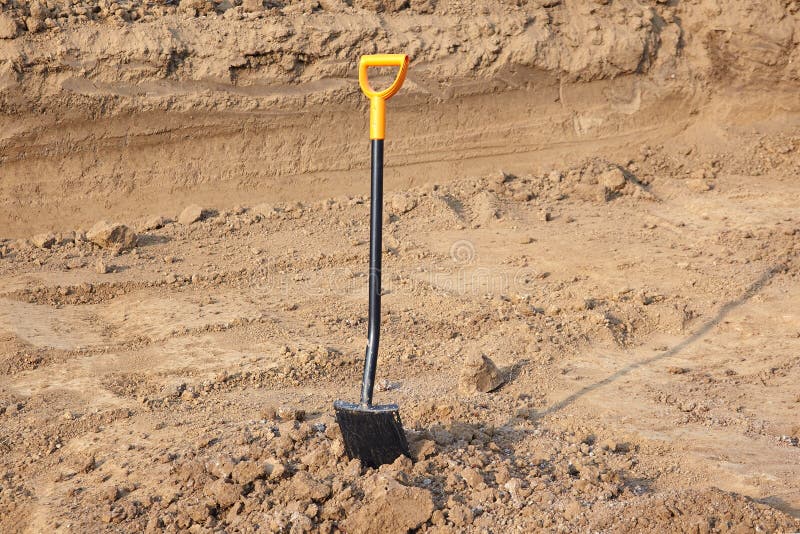 One shovel with bright yellow handle stuck to the ground. Ground works, excavations. royalty free stock image