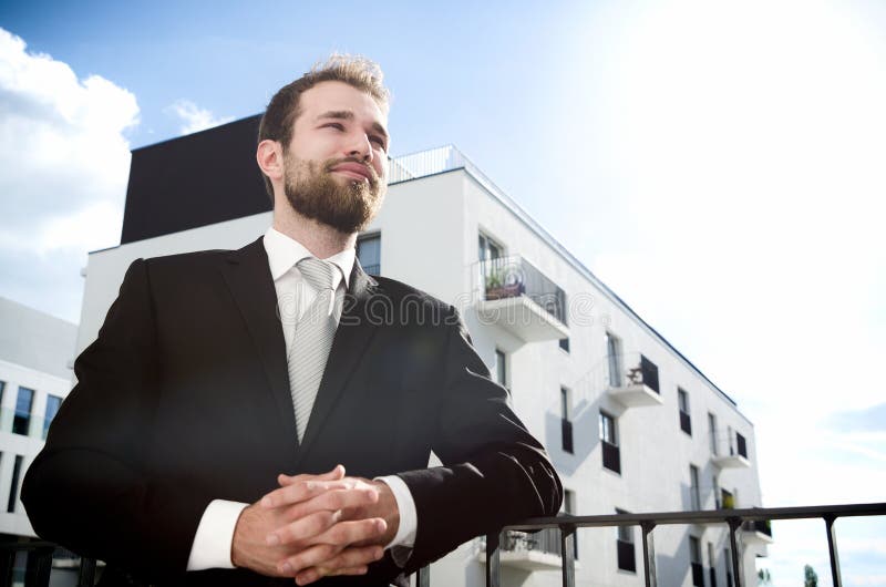 Relaxed businessman standing on balcony of his apartment. Businessman outdoor friendly caucasian suit balcony city apartment concept stock photography