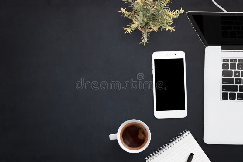 Smart phone and laptop on black office desk with copy space on left side stock image