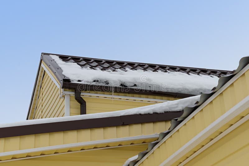 Snow and icicles on the roof. Of an apartment house is sheathed with siding stock photo