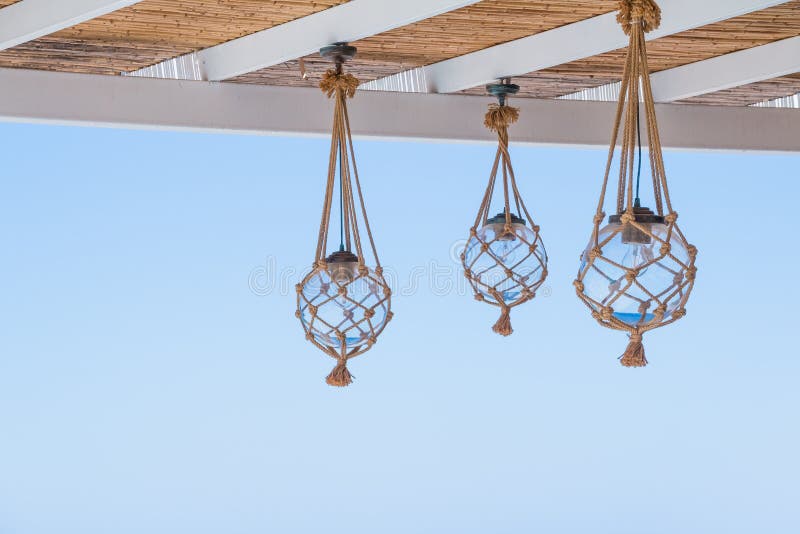 Straw cover the roof of a seaside terrace or veranda with hanging lantern and view to blue sky.many light bulbs stock image