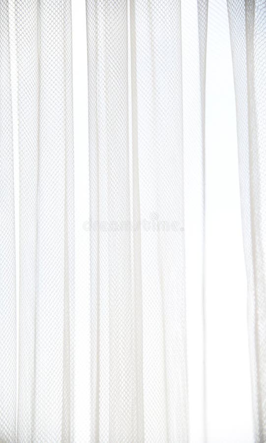 White tulle curtain with vertical folds. Window with light curtains. Soft textile texture. Light and shadow abstract royalty free stock image