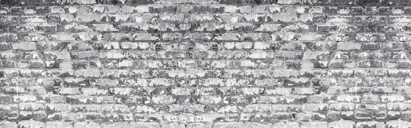 Wide light gray shabby brick wall texture. Old masonry with peeling white paint. Weathered brickwork panoramic background. Wide light gray shabby brick wall stock photography