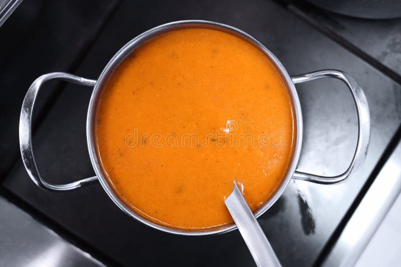 Yellow thick soup in a metal pot on the stove. Style and minimalism in the kitchen design royalty free stock photos