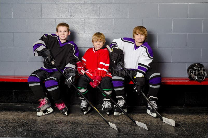 Youth Hockey Players in Dressing Room. Three Youth Boys Hockey Players Pose in Dressing Room in their equipment stock photo